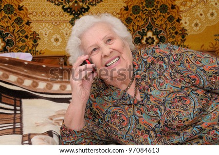 Senior woman speaks on the mobile phone in her bedroom