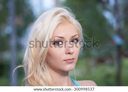 Portrait of the beautiful girl on the green blurry background of summer park