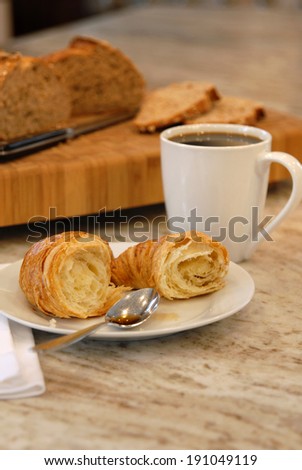Coffee cup with croissant on granite counter.