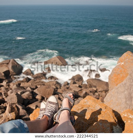 Couple in love sitting on the Cabo da Roca rocks and looking on atlantic ocean,the western point of Europe - Portugal