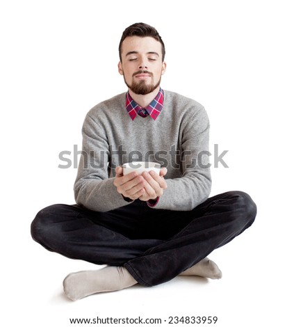Young pretty man sitting in lotus position with cup isolated on white background