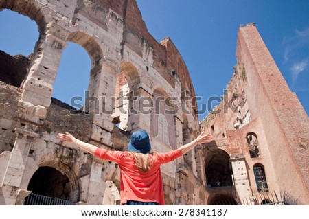 Happy young travel woman in summer hat  by Colosseum, Rome, Italy with arms raised out and up