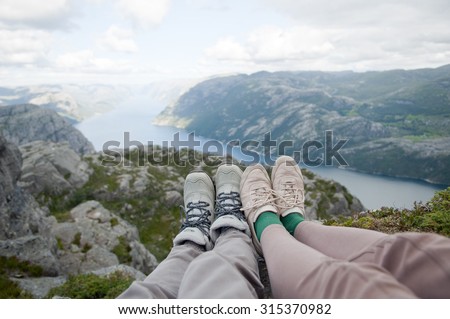 Two women friends sitting on the rocks of Preikestolen. Summer Norway landscape view