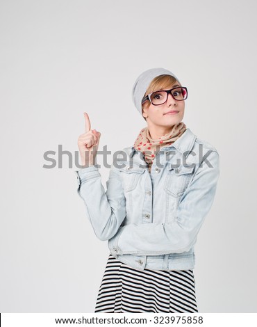 Beautiful young blond hair woman in glasses and hat  with finger point up. Hipster young and beautiful