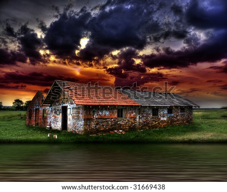 old abandoned ruined house near the river, against the strong beautiful dark colorful clouds
