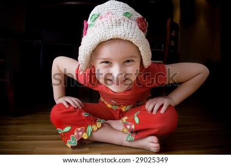 Small girl in summer hat sits on the floor