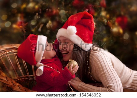 Portrait of happy mother and litlle baby in santa's hats Portrait of happy mother and litlle baby in santa's hats