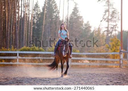 The young woman horseback riding at summer evening