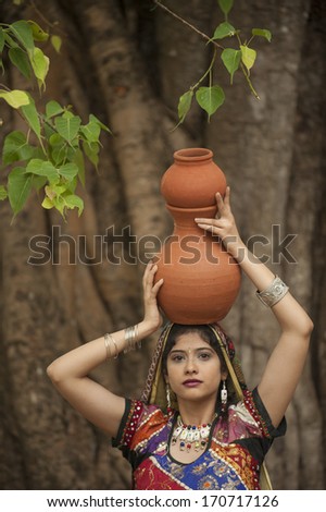 GUJARAT, INDIA - NOVEMBER 30: Unidentified Indian women in colorful traditional dress carry water in clay pots on November 30, 2011  in Gujarat, India