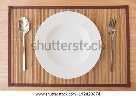 Empty plate spoon and fork on mat
