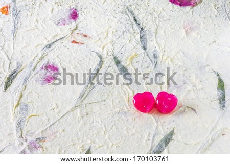 2 red heart candy on mulberry paper surface for sweet, love, romance, classic work. Pastel color background
