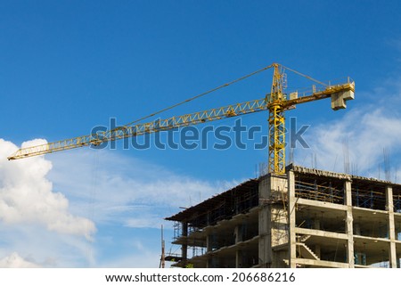 Yellow tower crane wide screen on blue sky background. Crane is building skyscraper in site.