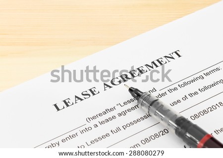 Lease agreement contract sheet and brown pen at bottom right corner on wood table background