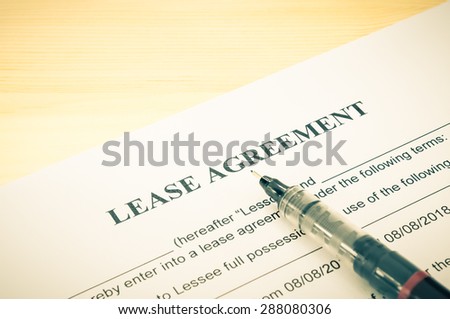 Lease agreement contract sheet and brown pen at bottom right corner on wood table background in vintage style