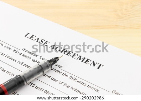 Lease agreement contract sheet and brown pen at bottom left corner on wood table background