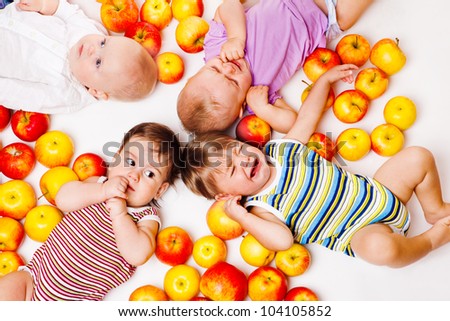 Four babies lying together among apples