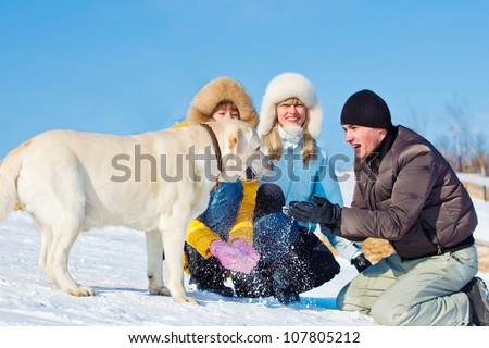 Laughing people and dog playing with snow
