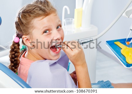 Little girl playing with dental drill at the dentist office
