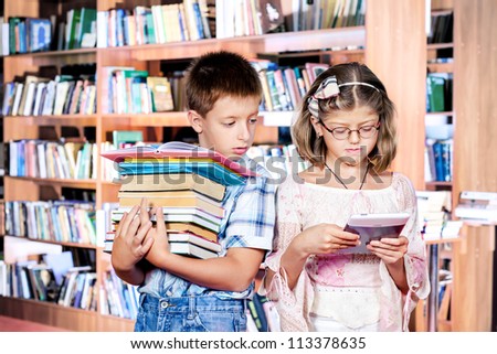 Boy with books pile and girl with e-reader