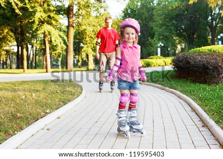 Preschool beginner in roller skates in front, and dad behind