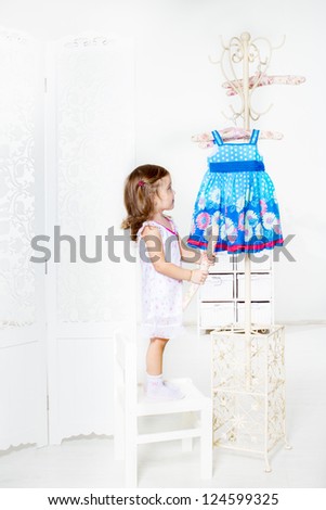 Girl looking on the coat rack with her dress hanging on it