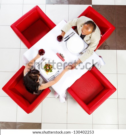 Top view on middle aged man and woman holding hands in a restaurant