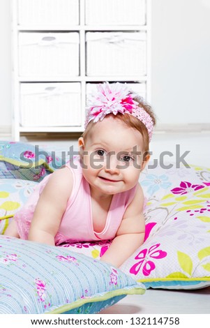 Lovely baby girl lying on the  pillows with floral pattern