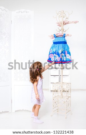 Little girl willing to get dress from the coat hanger