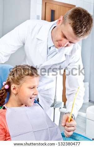 Dentist holding mirror for the girl to see her teeth