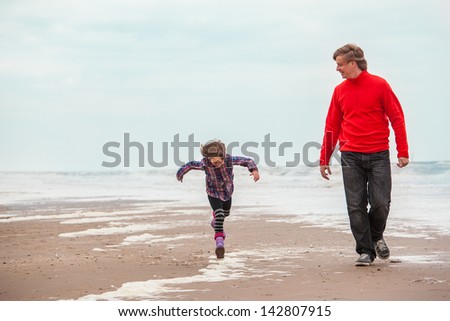 Dad and cheerful 6 years old girl walking along the seacoast