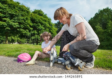 Father helping preschool daughter with her inline roller skates