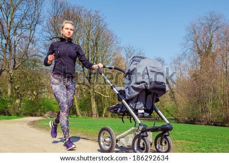 Young mother jogging with a baby buggy Young mother jogging with a baby buggy