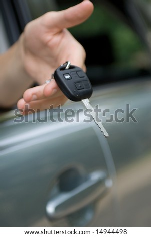 Car key in male hand, over silver car