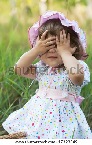 Little girl in pink hat playing peek-a-boo