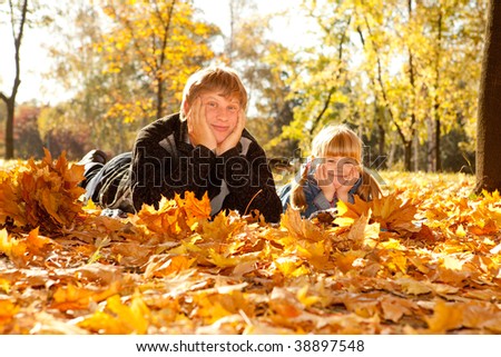 Daddy and daughter in autumn park lying on yellow leaves