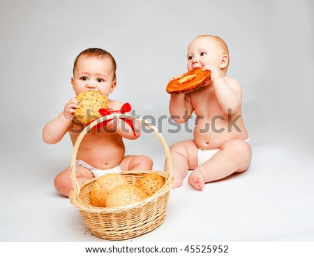 Two sweet babies in diapers eating buns