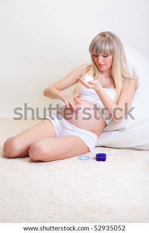Pregnant woman spreading cream over her tummy