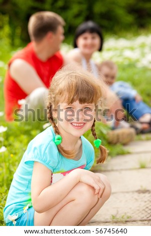 Lovely preschool girl in the outdoors, her family behind