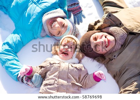Mom, dad and their daughter lie on snow