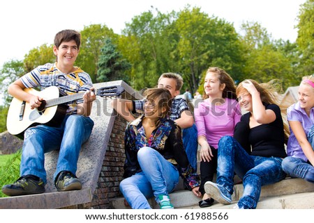 Cute teenage guy playing guitar for his friends