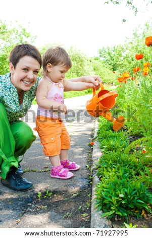 Toddler girl helping mom in the garden