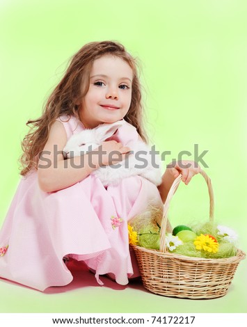 Curly little girl with Easter basket and white bunny in hands
