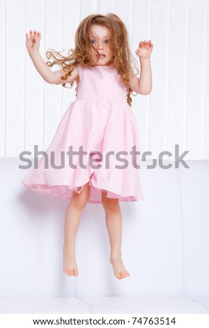 Sweet preschool girl jumping on the sofa