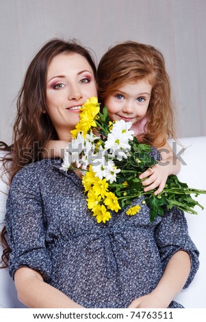 Sweet preschool girl embracing mom and presenting her flowers bunch