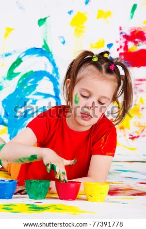 Lovely little girl dipping fingers into paint jar