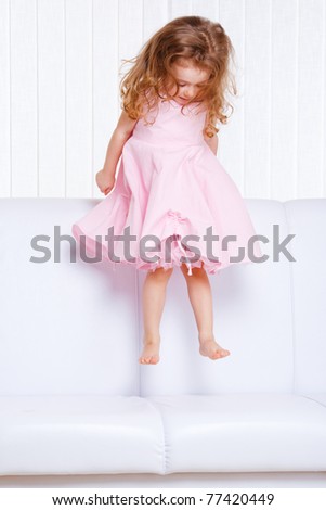Beautiful little  girl jumping on the sofa