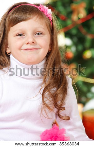 Sweet smiling preschool girl in front of Christmas tree
