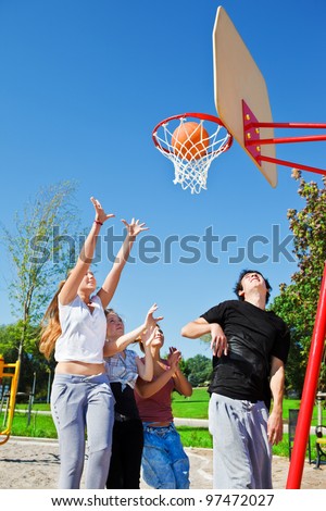 Teenagers throwing ball to the basketball hoop