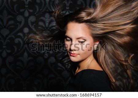 Beautiful Young Woman with long blowing hair, dark background