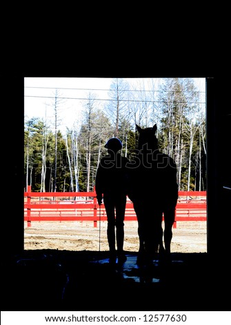 Silhouetted picture of a horse and rider exiting the barn.